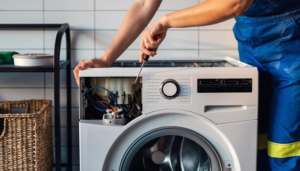Close-up of a technician working safely inside a washing machine control panel