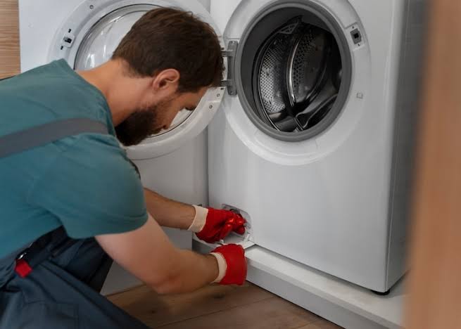 Technician servicing the lower access area of a front-loading dryer