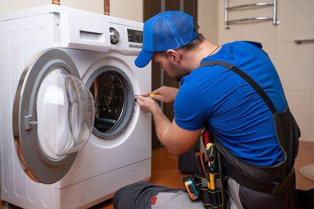 Technician servicing front-loading laundry appliances in a residential home